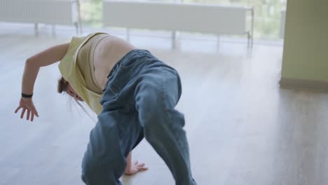 una chica joven bailando breakdance en un estudio moderno.