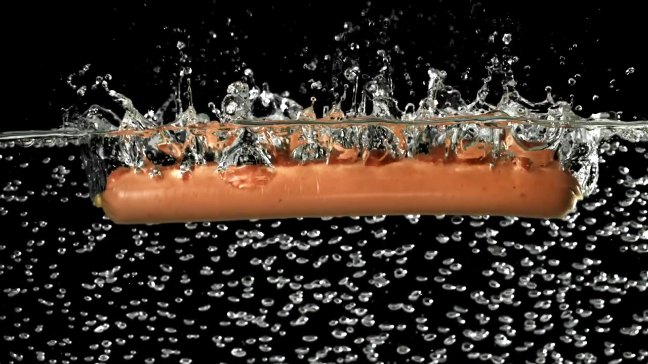 Salsiccia che cade nell'acqua con schizzi e bolle.