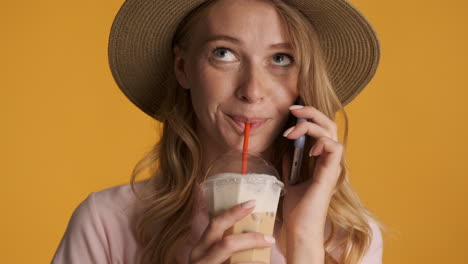 une femme caucasienne qui appelle en buvant du café glacé.