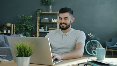cinemagraph de un hombre de oriente medio freelance trabajando con una computadora portátil y sonriendo
