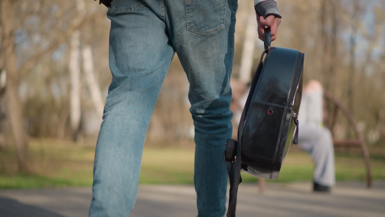 uomo con zaino che passa davanti a una panchina, uomo in abito bianco che passeggia accanto a una donna seduta con lo zaino, uomo bianco che trasporta uno zaino rotondo e cammina accanto a una donna seduta, sullo sfondo un paesaggio naturale sfocato