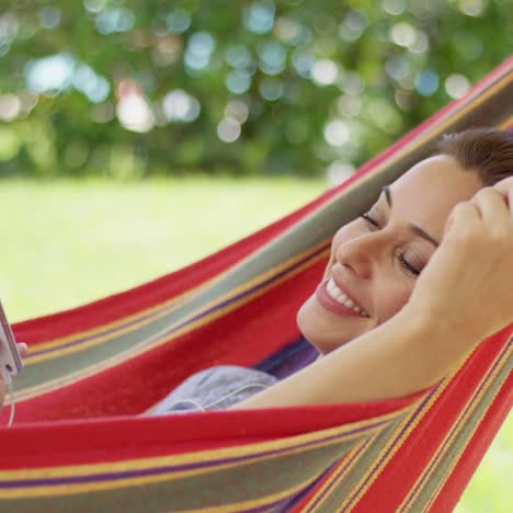 happy young woman listening to music in a hammock