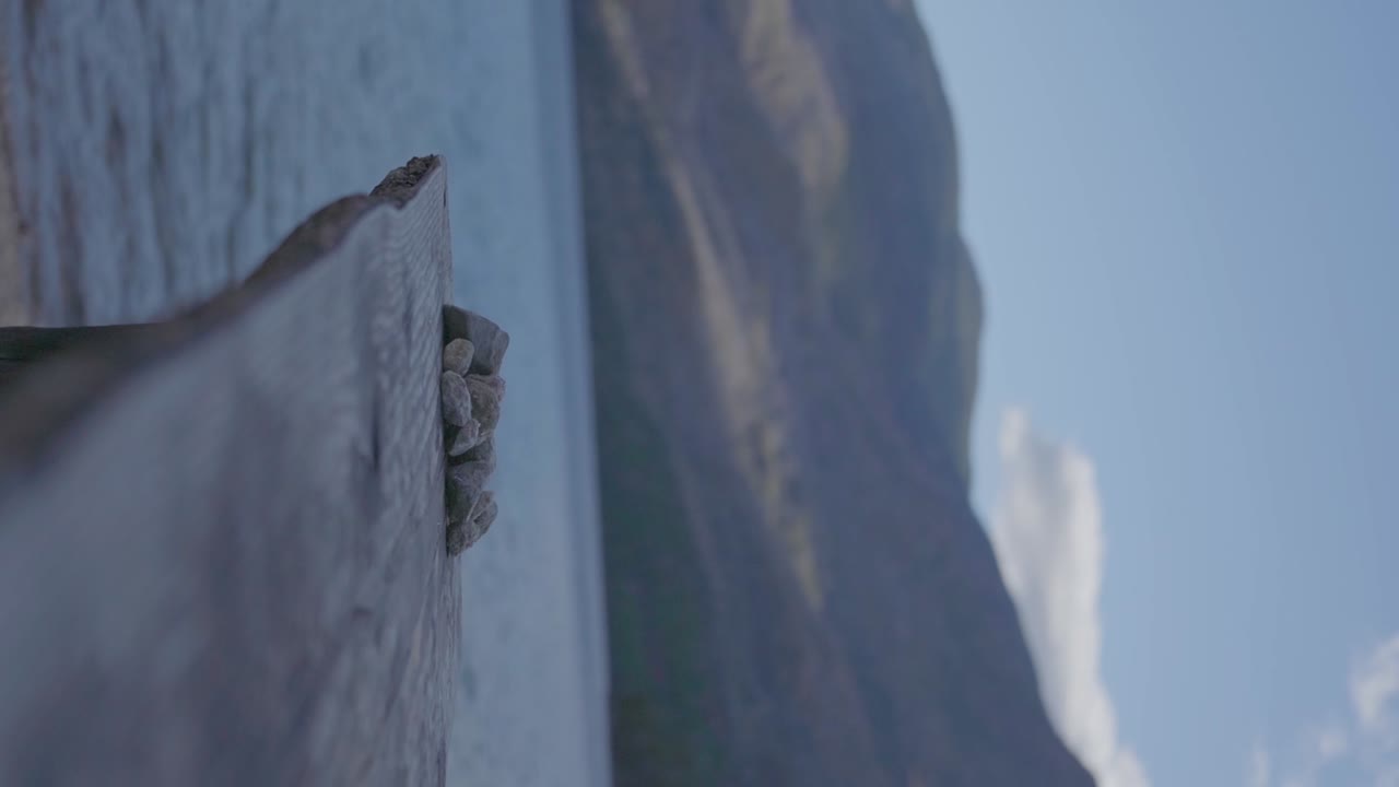 아르헨티나 파타고니아에 있는 산과 푸른 하늘이 있는 고요한 호수 옆에 나무 벤치와 자갈 돌 더미