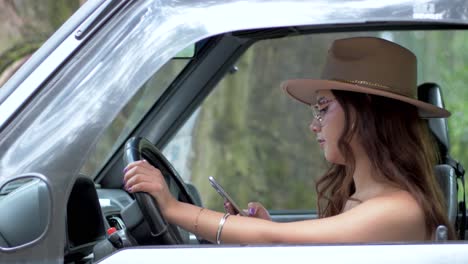 la elegancia moderna de una mujer ecuatoriana sonriente, sentada en el asiento del conductor, usando su teléfono móvil con gafas y un sombrero elegante