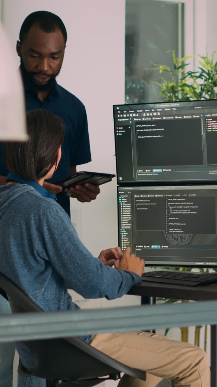 Vertical video: Diverse programmers collaborating on coding project compiling algorithm