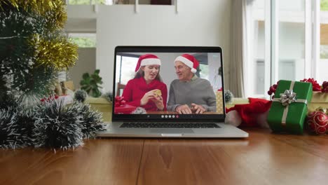 Lächelnder-Kaukasischer-Vater-Und-Tochter-Mit-Weihnachtsmützen-Bei-Einem-Weihnachtsvideoanruf-Auf-Dem-Laptop