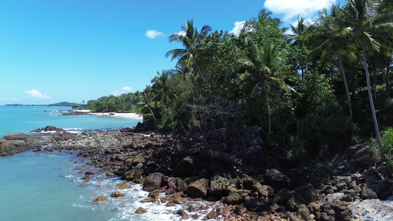 Prise de vues aériennes par drone d’une jungle tropicale dense le long du littoral de Koh Lanta en Thaïlande, montrant une forêt de palmiers luxuriante, des bords rocheux et une eau turquoise cristalline dans un cadre naturel isolé