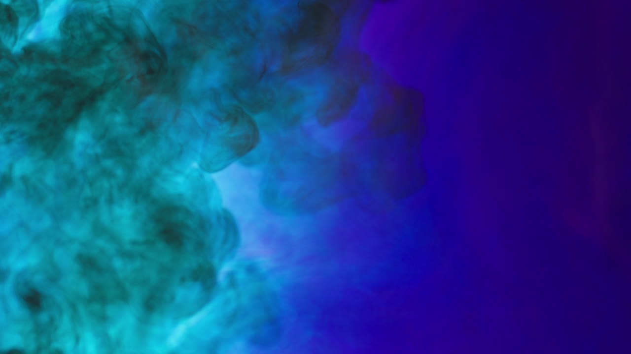 Black And Blue Paint Or Dye Dropped Into Water Against White Background To Create Swirling Colourful Smoke Background