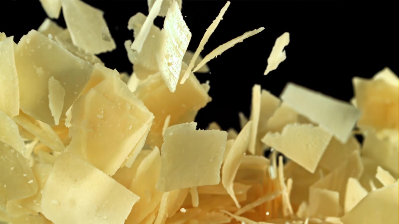 Copeaux de Parmesan tombant au ralenti sur fond noir