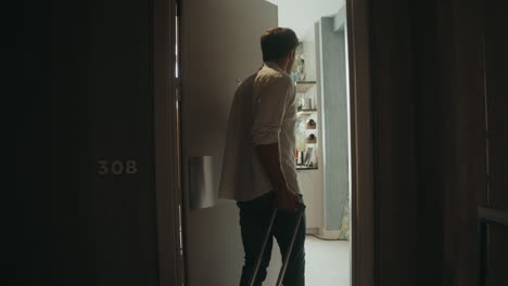 handsome guy with suitcase opening door hotel room. man coming luxury apartment.