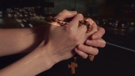 animation of hands of caucasian woman holding rosary and praying over road traffic