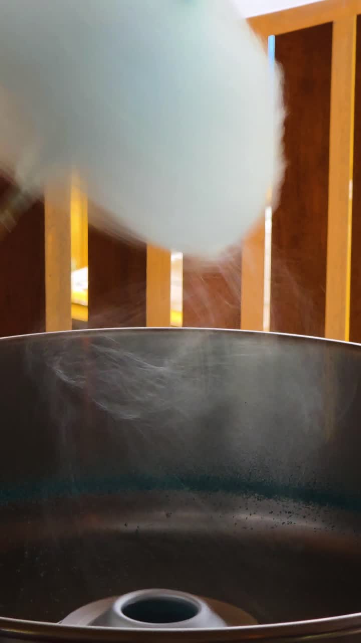 Whisps of sugar spin into fluffy blue cotton candy as the treat is made fresh in vertical view