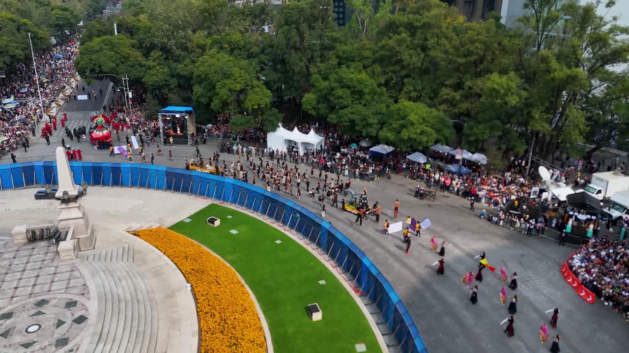 Orbital aeiral shot of citizen participation in the Day of the Dead parade marching at the Angel of Independence roundabout in Mexico City