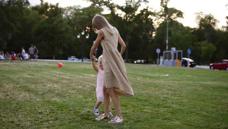 Loving-Mother-In-Beige-Dress-With-Her-Little-Daughter-Having-Fun-And-Playing-In-The-Park