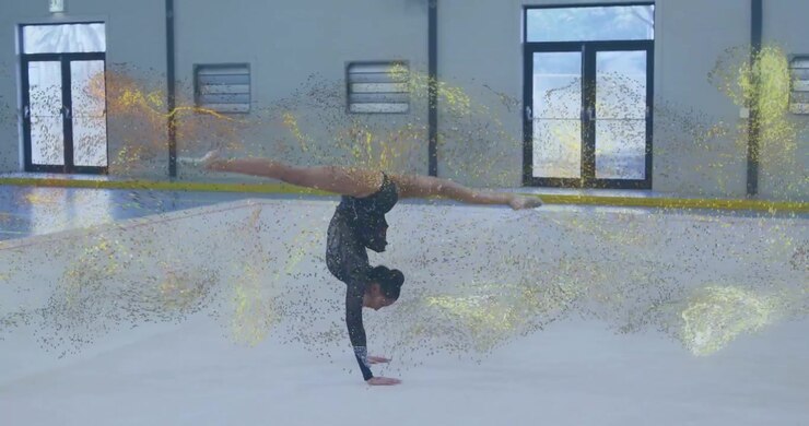 golden particles drifting in, gymnast arching into handstand then bowing ending fitness routine