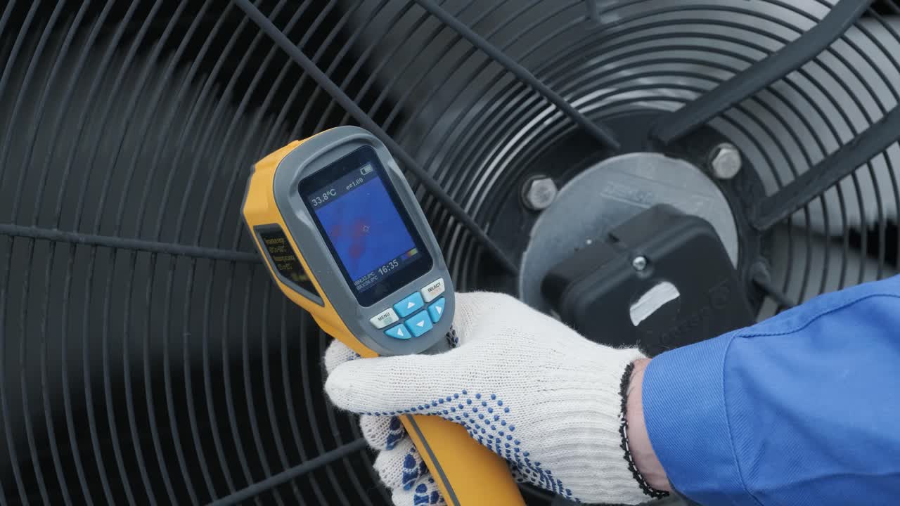 el técnico utiliza un termómetro infrarrojo de imagen térmica para comprobar el intercambiador de calor de la unidad de condensación