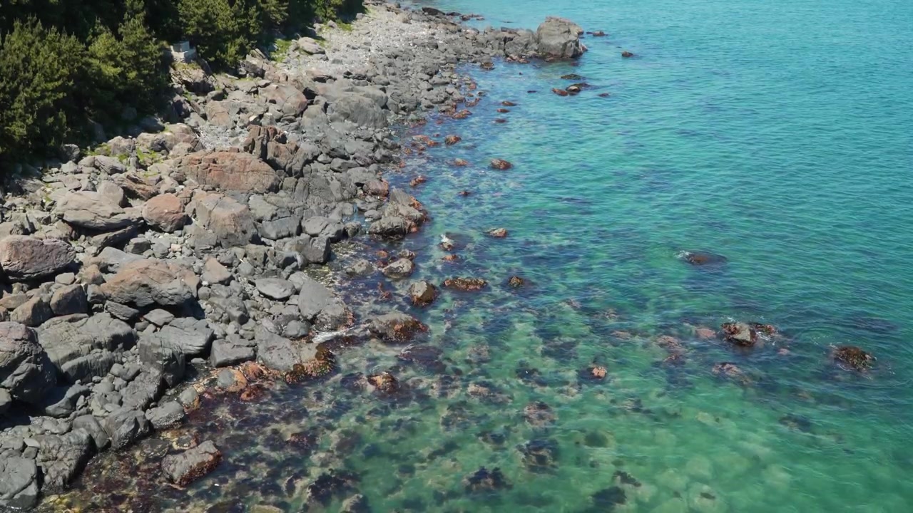 Busan, Güney Kore'deki Haeundae Mavi Hat Parkı sahilinde kayalık kıyı boyunca kristal berraklığında turkuaz suyla buluşan engebeli kayalar