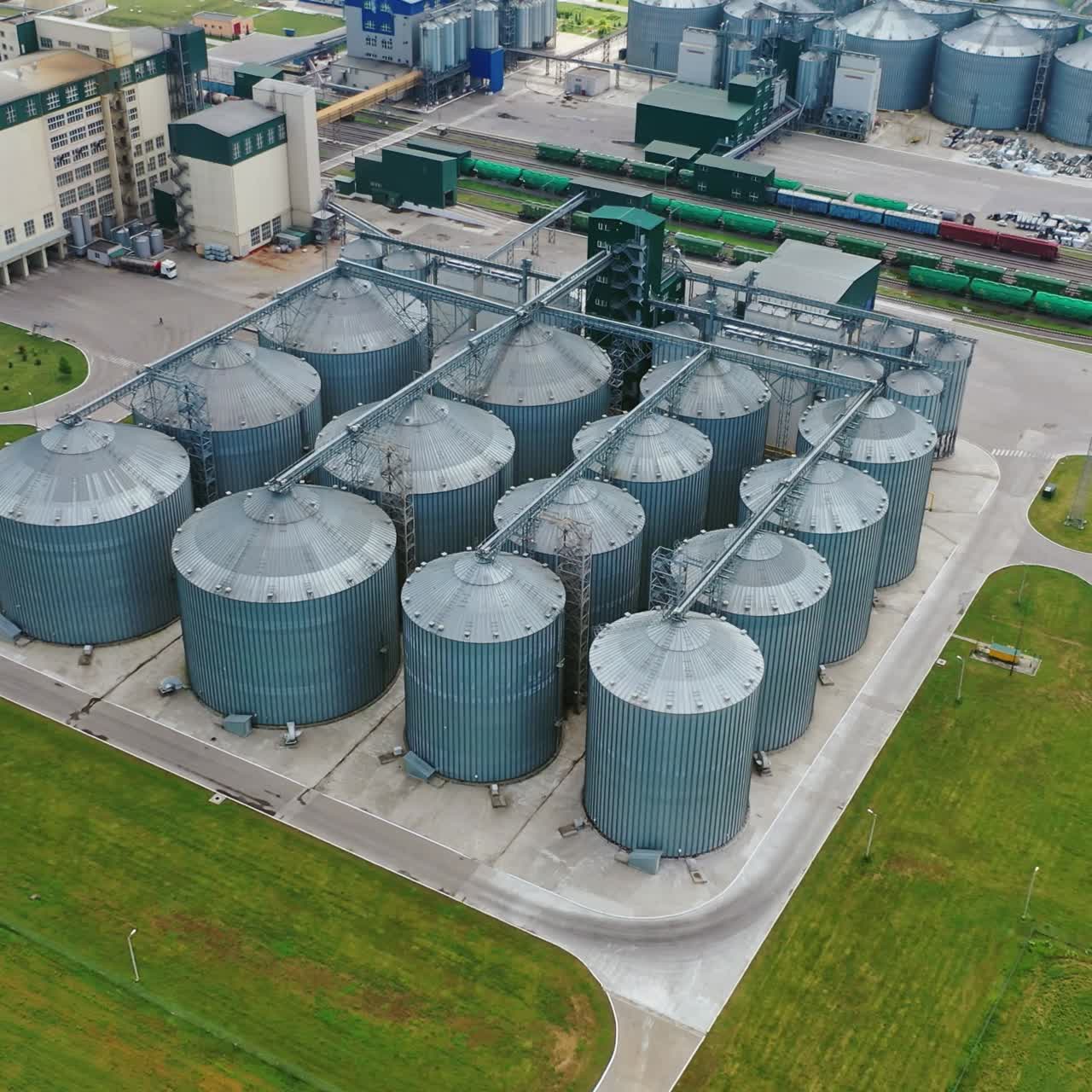 Agricultural land and grain silo elevator. Steel grain silos elevators storage on field. Agriculture Industry. Aerial view.
