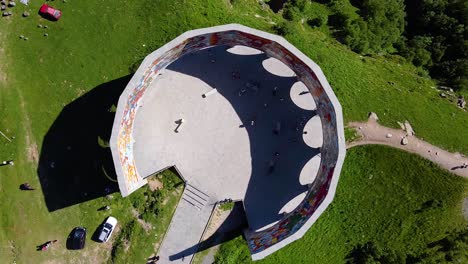 Cinematic-drone-shot-from-top-down,-showing-an-ancient-monument-in-Georgia-in-front-of-beautiful-mountains