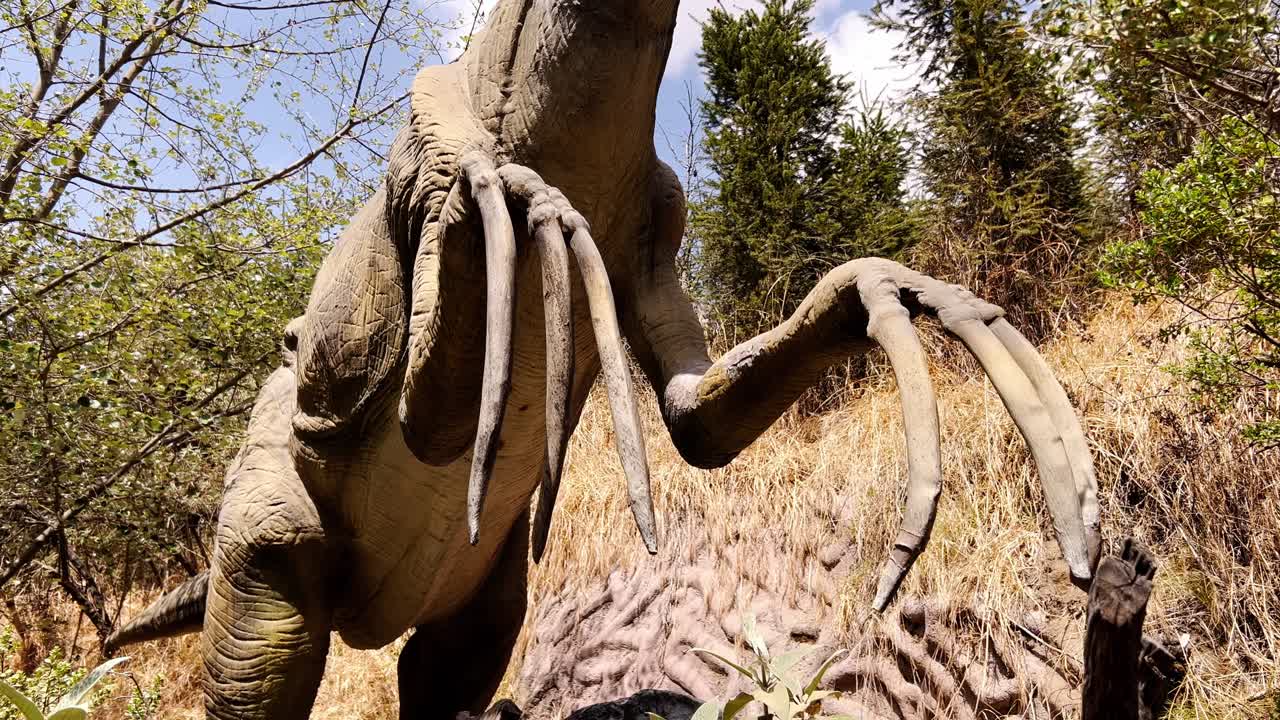 Close-up of the moving paws with long fingers of a Compsognathus dinosaur, a replica of the prehistoric creature in an amusement park