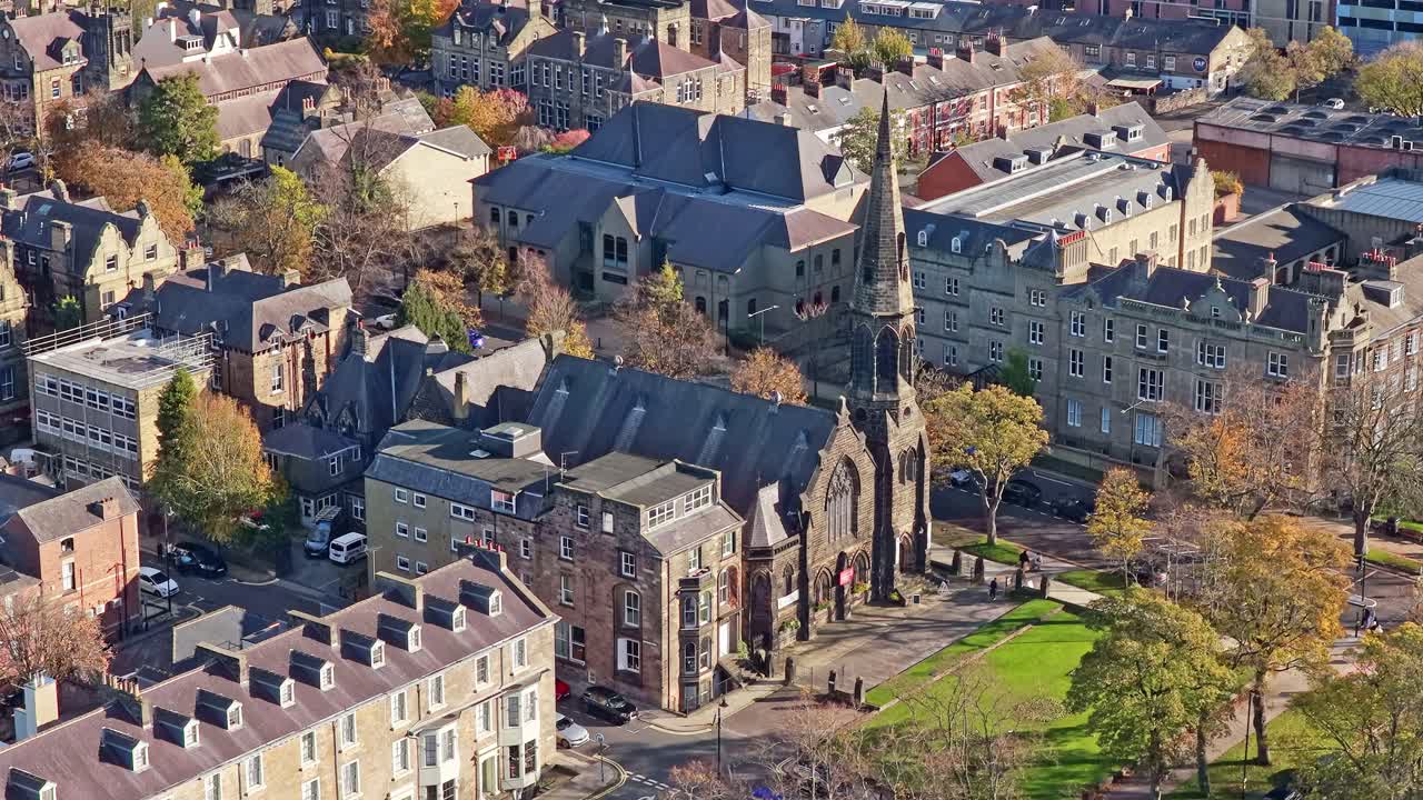 Aerial of Saint Peter’s Church, Harrogate: pointed Victorian spire, ornate sandstone architecture, autumn trees, city centre gardens, and enclosing heritage buildings