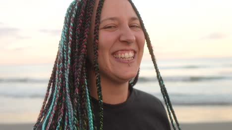 mujer con trenzas se ríe mirando la cámara en la playa