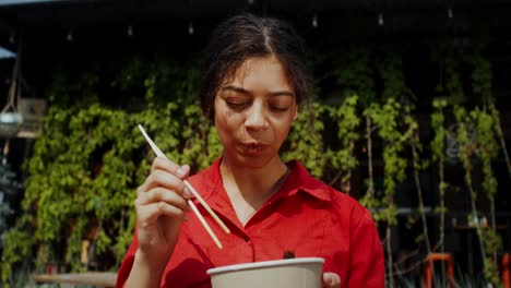 mujer comiendo fideos al aire libre