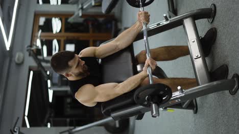 un guapo culturista haciendo levantamiento de pesas en el gimnasio