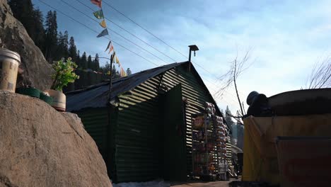 clip en cámara lenta de la tienda de té himachal en sethan manali banderas coloridas y línea de árboles detrás del viaje estético cinematográfico