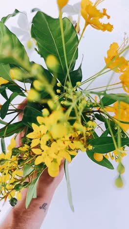 hand holding a bouquet of yellow flowers