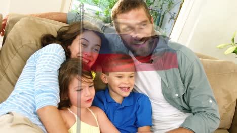 animación de la bandera de rusia sobre una feliz pareja caucásica abrazando a su hijo e hija en casa