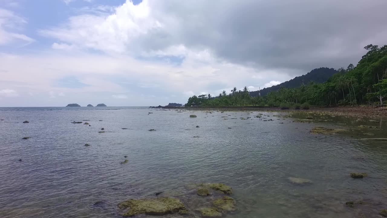 toma aérea del carro lateral del océano poco profundo con rocas y costa de la isla