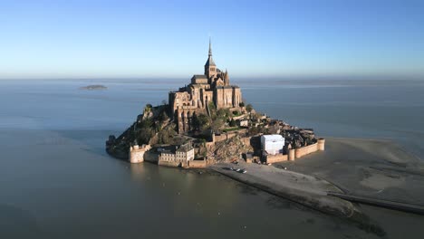 french mont saint michel castle in normandy france, aerial drone flying around in broad daylight at high tide