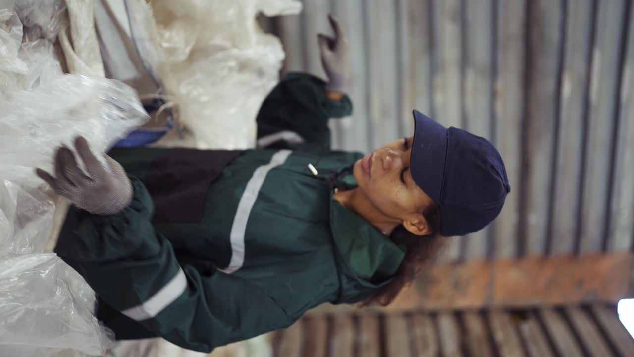 An African-American woman in a special uniform sorts polyethylene at a waste recycling plant. Processing of raw materials, recycling. Pollution control
