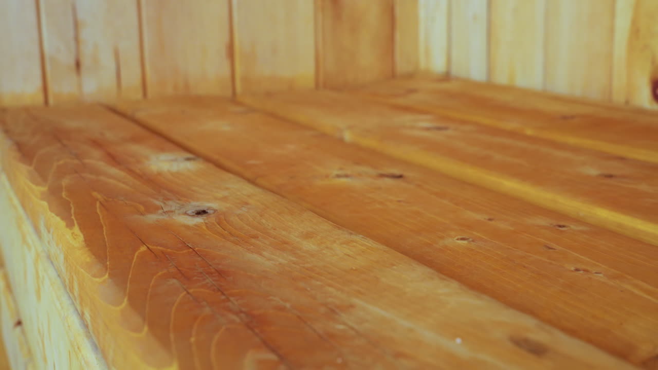 Close up of rustic sauna wooden table featuring rich warm hues and prominent wood grain, displaying natural imperfections, knots, and texture that highlight handcrafted charm