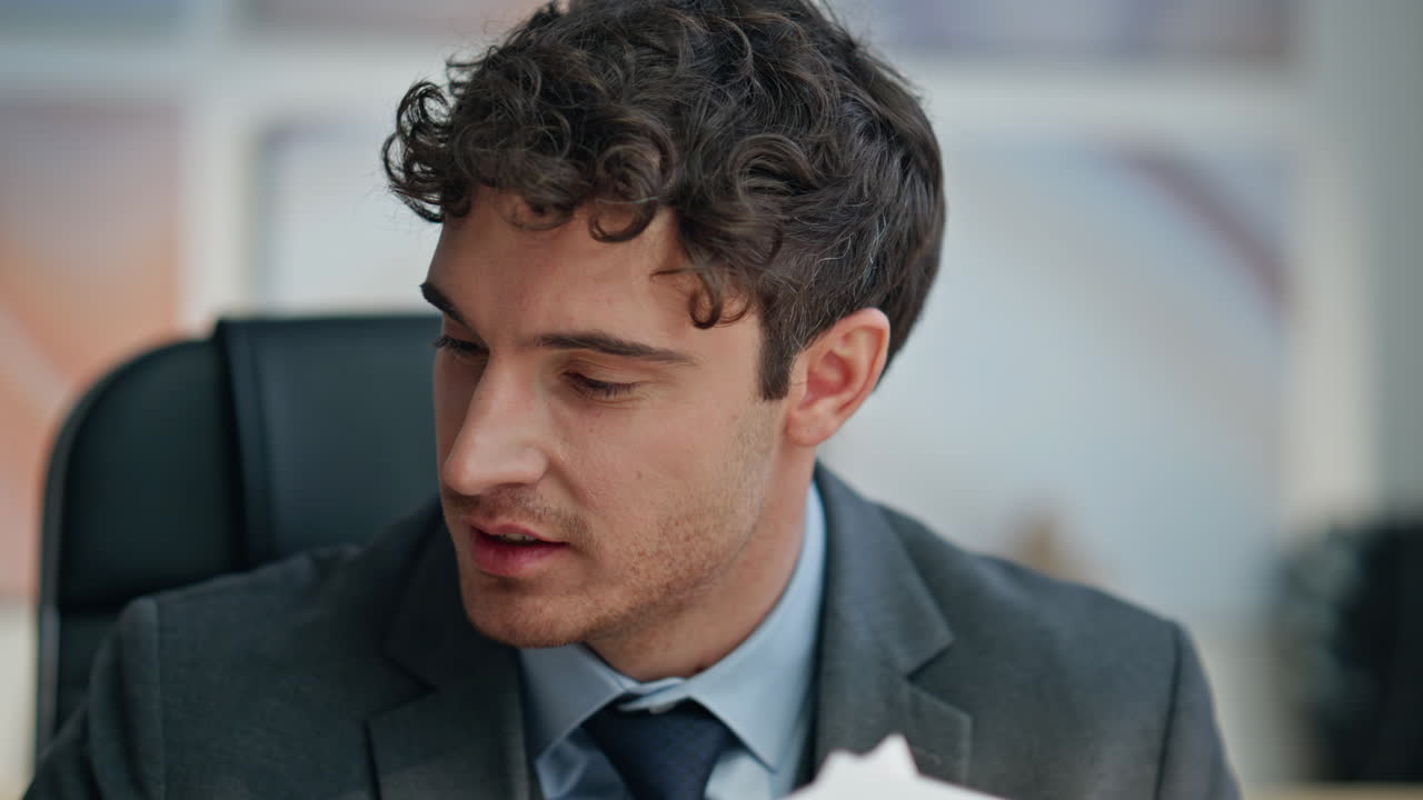 Uomo d'ufficio che lavora con documenti alla sua postazione, primo piano. Manager sorridente che studia documenti.