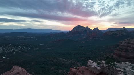 tourist standing on the edge of the cliff, enjoying scenic landscape of sedona in arizona at sunset - aerial drone shot