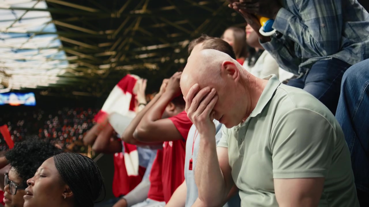 Anspændt fodboldfan på stadiontribunen, der taber et live fodboldvæddemål