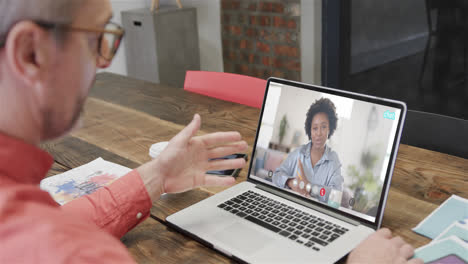 hombre de negocios caucásico en una llamada de video portátil con una colega afroamericana en la pantalla