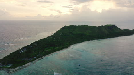tropical island with dense forest and curved bay in turquoise lagoon