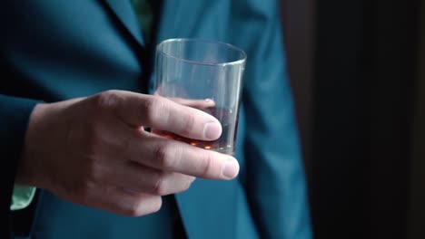 man in suit holding a glass of liquor