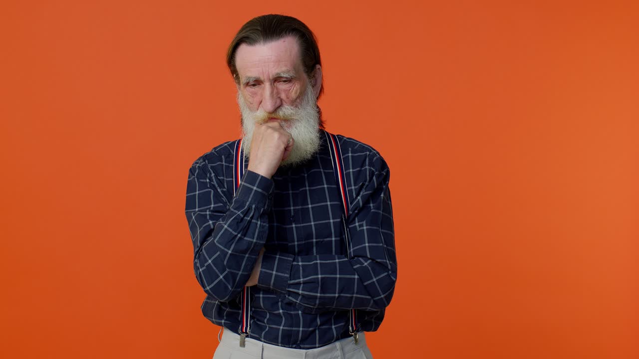Thoughtful clever senior old bearded man rubbing his chin pondering a solution, doubting question