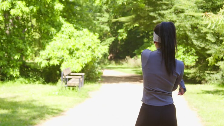 Young Woman Stretching Before Exercising Running Through City Park Wearing Wireless Earbuds 1