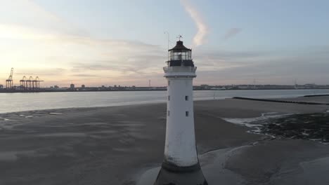 low tide aerial view coastal lighthouse sunrise shipping port cranes horizon rising tilt down