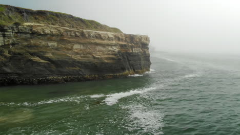 aerial fly over cliffside on foggy ocean