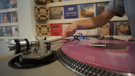 dj colocando el lápiz óptico en vinilo rosa mientras la mesa giratoria comienza a girar la toma del cardán en cámara lenta