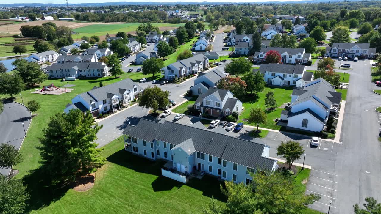 Immeubles d’appartements modernes dans une ville de banlieue américaine rurale par une journée ensoleillée. Prise de vue aérienne rapprochée. Saison automnale avec des voitures garées sur le parking. Terres agricoles en arrière-plan