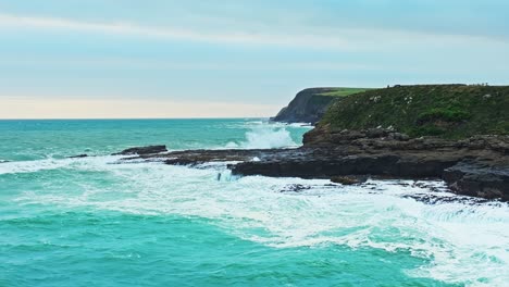 water drains between heavily eroded cliff ledges of curio bay