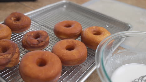 hands putting fresh homemade donuts on wire cooling rack, slow motion