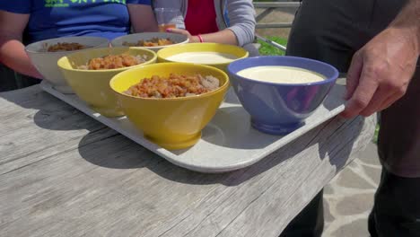 farmer bringing plate full of bowls with sour milk and buckwheat porridge